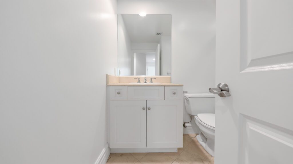 Bathroom with a sink, toilet, and large rectangular mirror