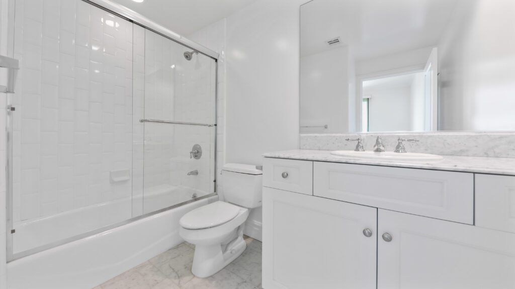 Shower area, toilet, and sink in a white bathroom